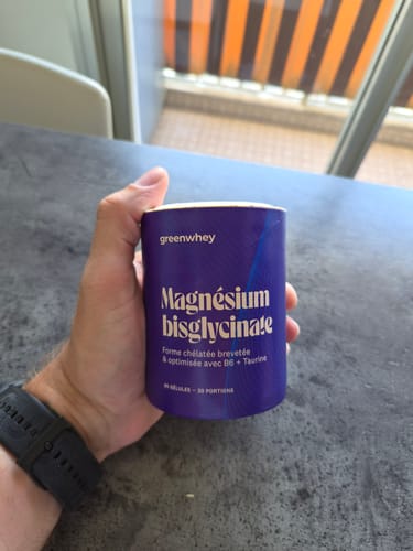 Client tenant le pot violet de Magnésium Bisglycinate dans sa main.