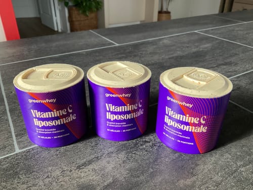 Photo d'un client montrant trois pots de Vitamine C liposomale sur un comptoir carrelé.