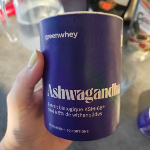 Customer's hand holding the dark blue pot of Ashwagandha bio KSM-66 supplement, close-up.