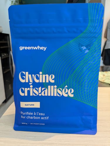 Un client montre le sachet bleu de Glycine cristallisée posé sur une table.