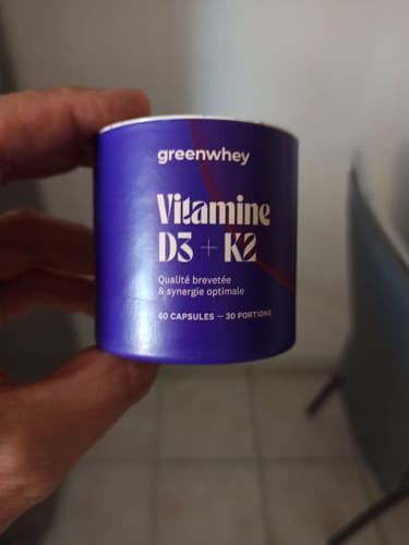 Un client tient le pot violet de Vitamine D3 + K2 dans sa main.