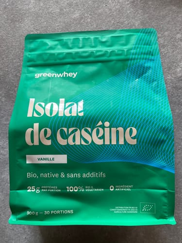 Sachet vert d'Isolat de Caséine d'un client, saveur vanille, posé sur une surface grise.
