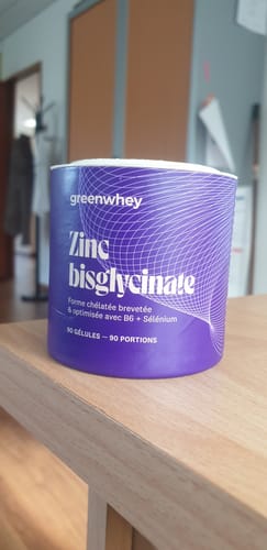 Customer's violet Zinc Bisglycinate container with white text, resting on a light wooden table.