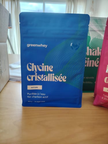 Le sachet bleu de Glycine cristallisée d'un client posé sur une table en bois.