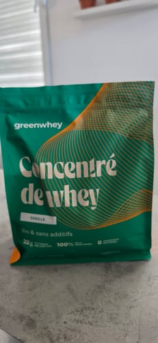 Client montrant son sachet vert de Concentré de whey saveur vanille sur un comptoir.