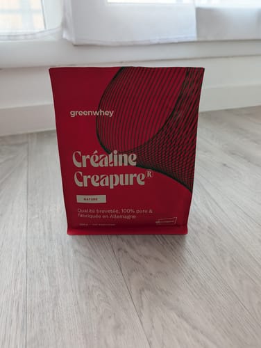 Le sachet rouge de Créatine Creapure® d'un client, posé sur un sol en bois.