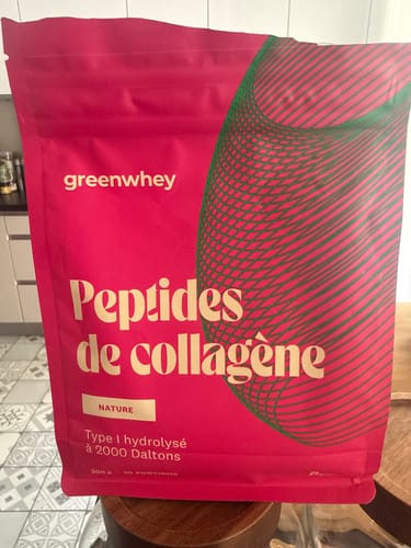 Un client montre le sachet rose de Peptides de Collagène, saveur Nature, posé dans une cuisine.