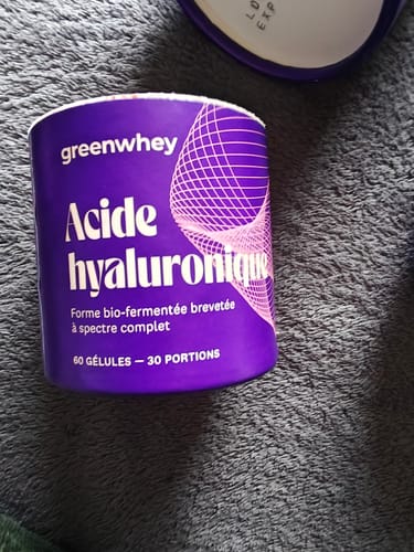 Reviewer's pot d'Acide hyaluronique violet avec couvercle ouvert sur un support gris texturé