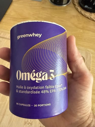 Client tenant dans sa main le pot en carton violet du produit Oméga 3 EPAX®.