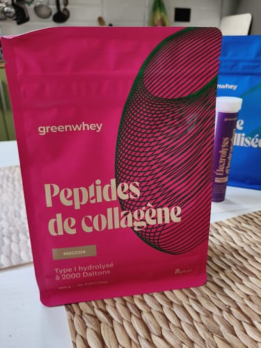 Photo d'un client montrant le sachet rose de Peptides de Collagène, saveur moccha, sur un set de table.