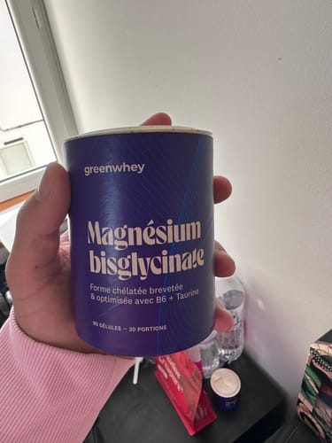Client tenant le pot cylindrique de Magnésium Bisglycinate dans sa main.