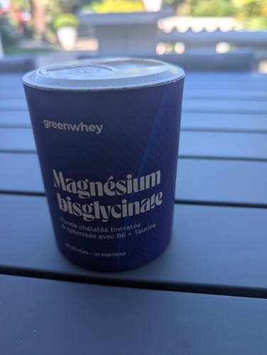 Gros plan du client sur le pot de Magnésium Bisglycinate posé sur une table.