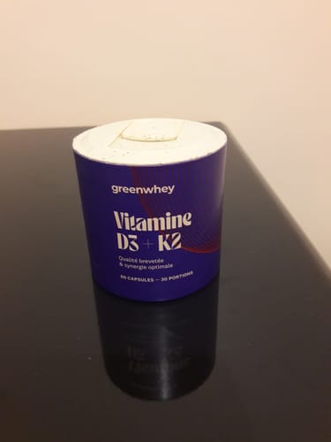 Le pot en carton violet de Vitamine D3 + K2 du client sur une table.
