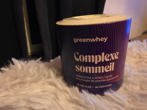 Un client montre le pot de son Complexe Sommeil sur une surface blanche et pelucheuse.