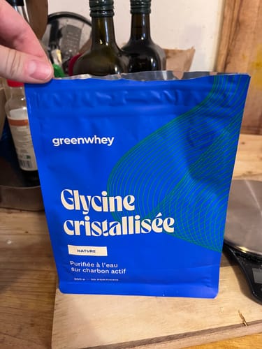 Un client tenant le sachet bleu de Glycine cristallisée sur un comptoir de cuisine.