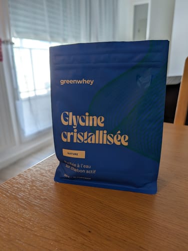 Client montrant son sachet de Glycine cristallisée sur une table en bois.